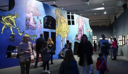 Visitantes ante una reproducción de las ilustraciones de Lola Anglada en la exposición  «Los mundos de Alicia. Soñar el país de las maravillas»