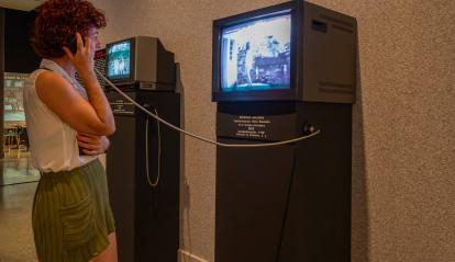 Visitant interactuant amb vídeos de cinema doméstico a l'exposició «[Rec]ords. La vida a través del cinema domèstic» a CaixaForum València.