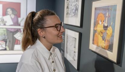 Una visitant somriu observant una de les vinyetes exposades a CaixaForum Girona.