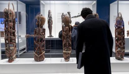 Un hombre observando las figuras malangan de canoa de Nueva Irlanda, presentes en la exposición «Voces del Pacífico». 