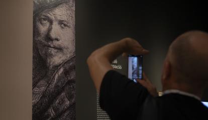 Un hombre fotografiando una de las obras de la exposición «Rembrandt. Un mundo en grabados», en CaixaForum València.