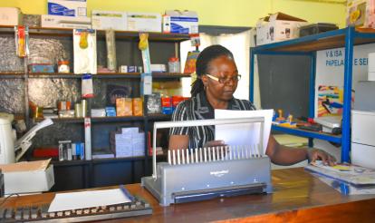 Crisália Nhambi working in her stationery shop.