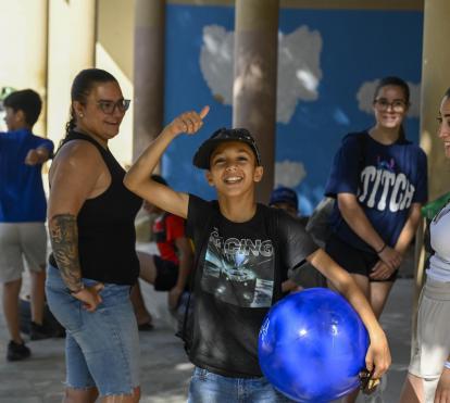 Un niño beneficiario del programa CaixaProinfancia sonríe a cámara sujetando una pelota.