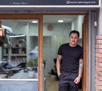 Juan Gabriel Agudelo en la entrada de su barbería, The Clipper Club, en Barcelona.