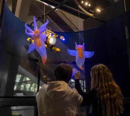  Two visitors observe the fictional beings at the entrance to the exhibition.