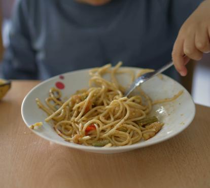 A boy eating a plate of pasta.