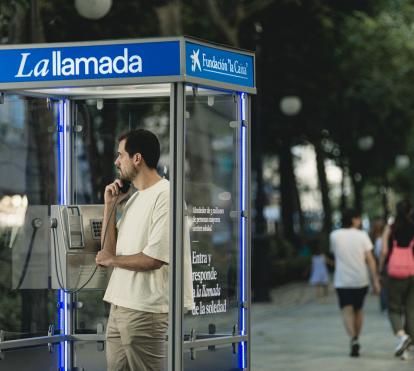 Un chico joven escuchando el testimonio de una persona mayor desde la cabina telefónica en Granada.