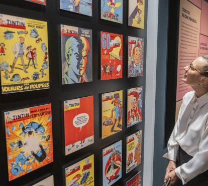 Una visitant de l'exposició «Còmic. Somnis i història» observant les diverses portades de l'icònic «Tintin». 