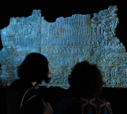 Dos visitantes admirando una de las piezas presentes en la exposición «Asurbanipal» en CaixaForum Madrid. 