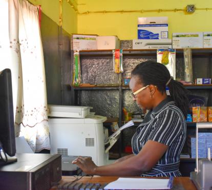 Crisália Nhambi working in her stationery shop.