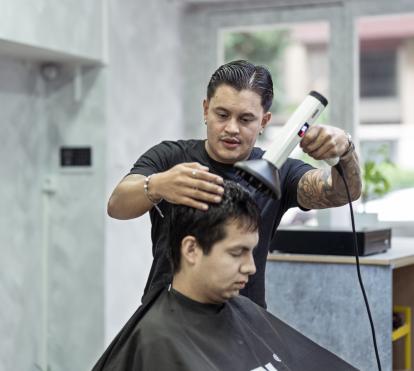 Juan secándole el pelo a un cliente.