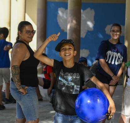 Un niño beneficiario del programa CaixaProinfancia sonríe a cámara sujetando una pelota. 