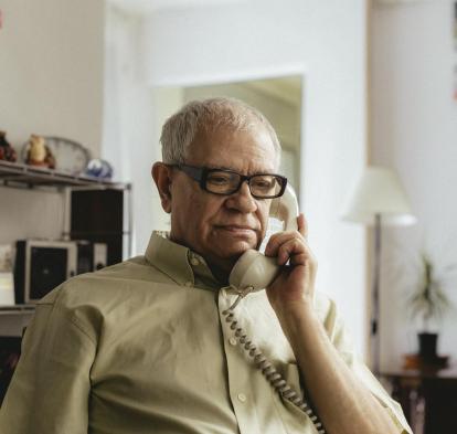 An elderly person talking on the phone.