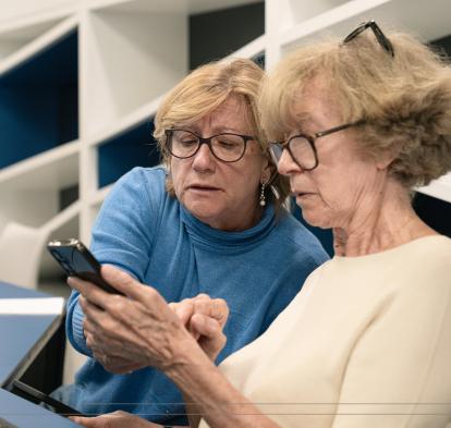 Dues senyores aprenen a fer servir un smartphone durant els tallers Competències Digitals +60.