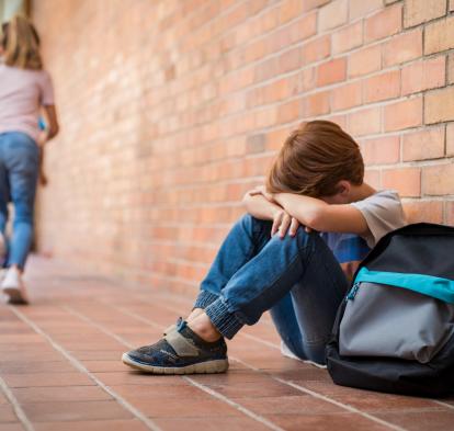 Niño solo en el patio de una escuela. 