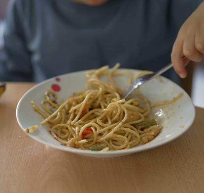 A boy eating a plate of pasta.