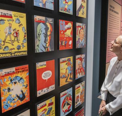 Una visitant de l'exposició «Còmic. Somnis i història» observant les diverses portades de l'icònic «Tintin». 