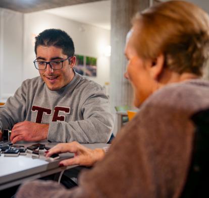 El voluntario Adrián Casado juega al dominó con Luisa.