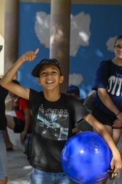 Un niño beneficiario del programa CaixaProinfancia sonríe a cámara sujetando una pelota.