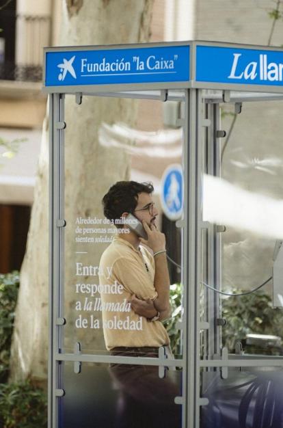 A young man listening to an older person's testimony from a phone booth.