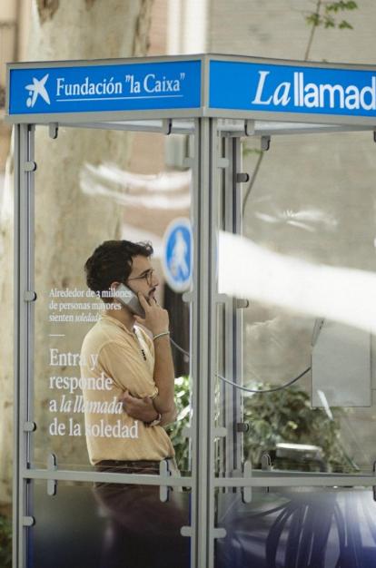 Un chico joven escuchando el testimonio de una persona mayor desde la cabina telefónica. 