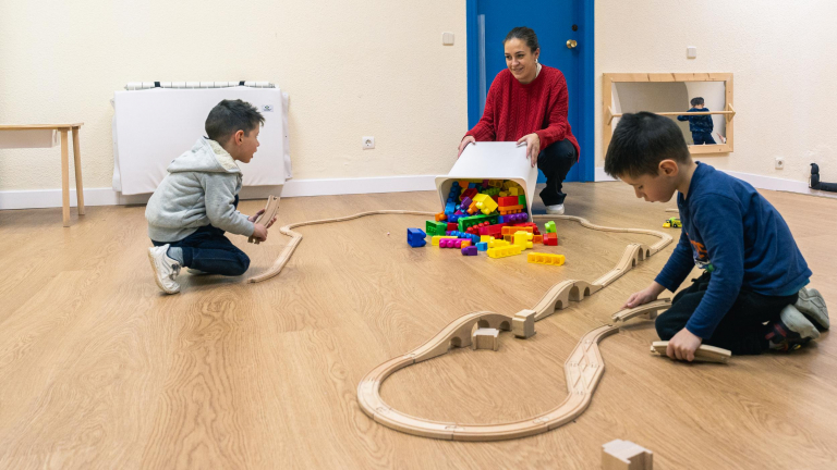 Dos niños y una técnica juegan con un circuito de coches de juguete en los Espacios de Crecimiento 3-6 de CaixaProinfancia en la Asociación Barró.