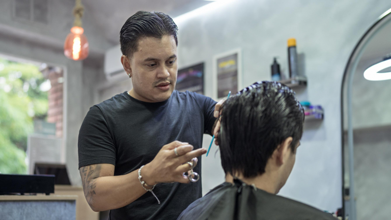 Juan Gabriel Agudelo tallant els cabells a un dels seus clients.