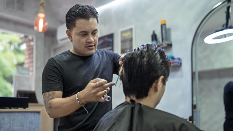 Juan Gabriel Agudelo cortándole el pelo a uno de sus clientes.
