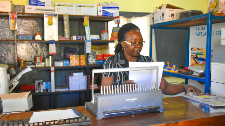 Crisália Nhambi working in her stationery shop.