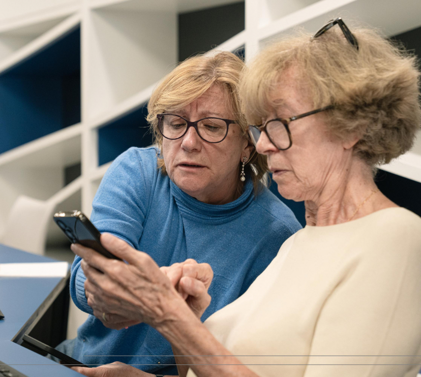 Dues senyores aprenen a fer servir un smartphone durant els tallers Competències Digitals +60.