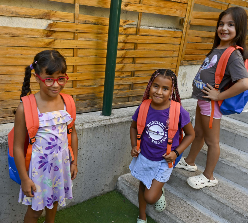 Tres nenes usuàries del programa CaixaProinfància amb les motxilles noves per afrontar el nou curs.