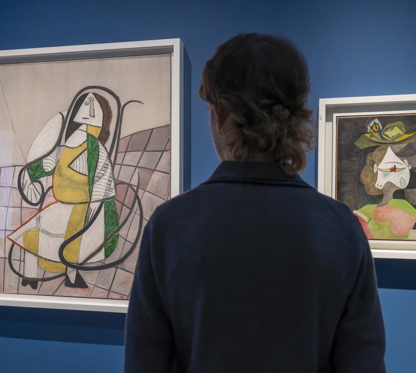 Una visitant observant dues pintures de l'exposició «Art i natura. Un segle de biomorfisme».