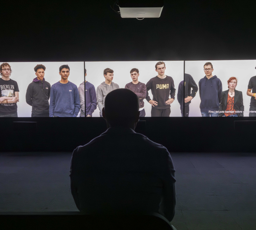 Visitor in front of the three-channel video installation of the exhibition Out of Frame. Works by Rineke Dijkstra and Philippe Parreno.