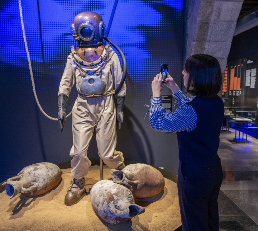 Una visitant de l'exposició aprofita per fotografiar un antic uniforme de submarinisme.