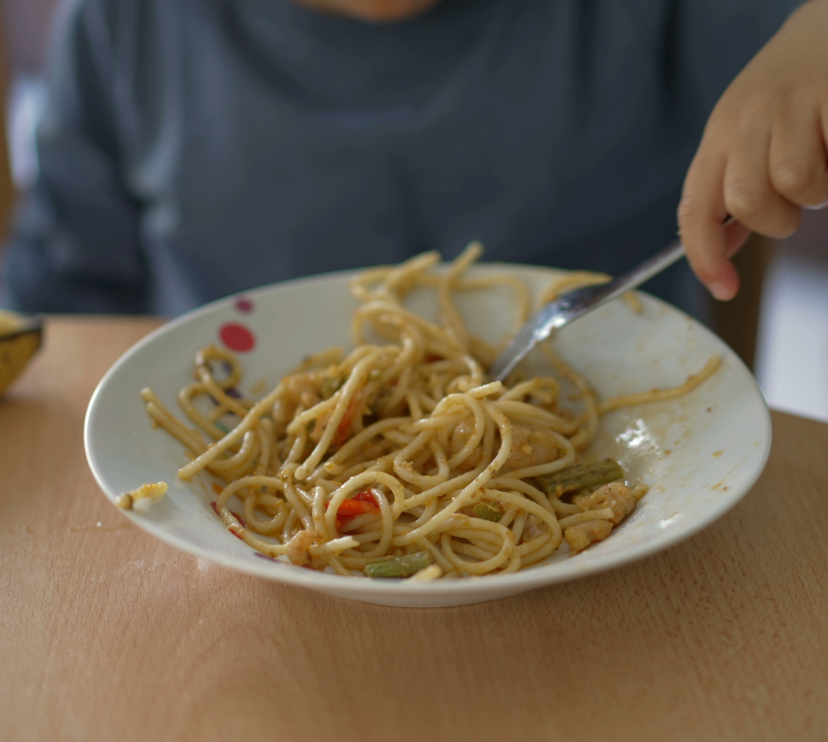Un nen dinant un plat de pasta.