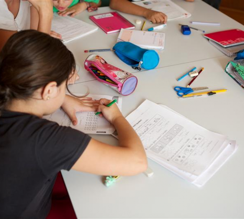 Una nena fent deures en una aula.