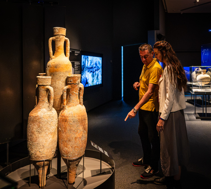 Dos personas observando algunas de las piezas presentes en la muestra «Naufragios. Arqueología sumergida» en CaixaForum Zaragoza. 