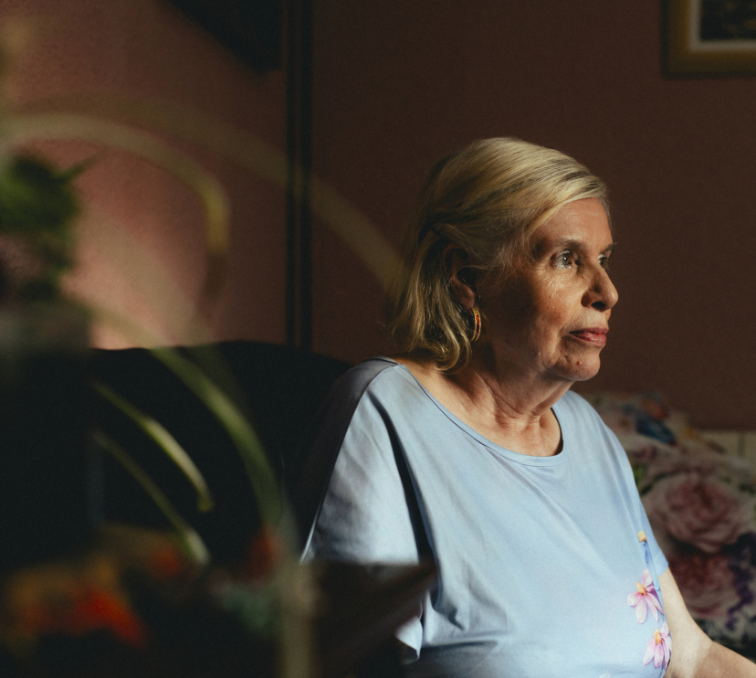 Una dona gran asseguda sola a casa seva.