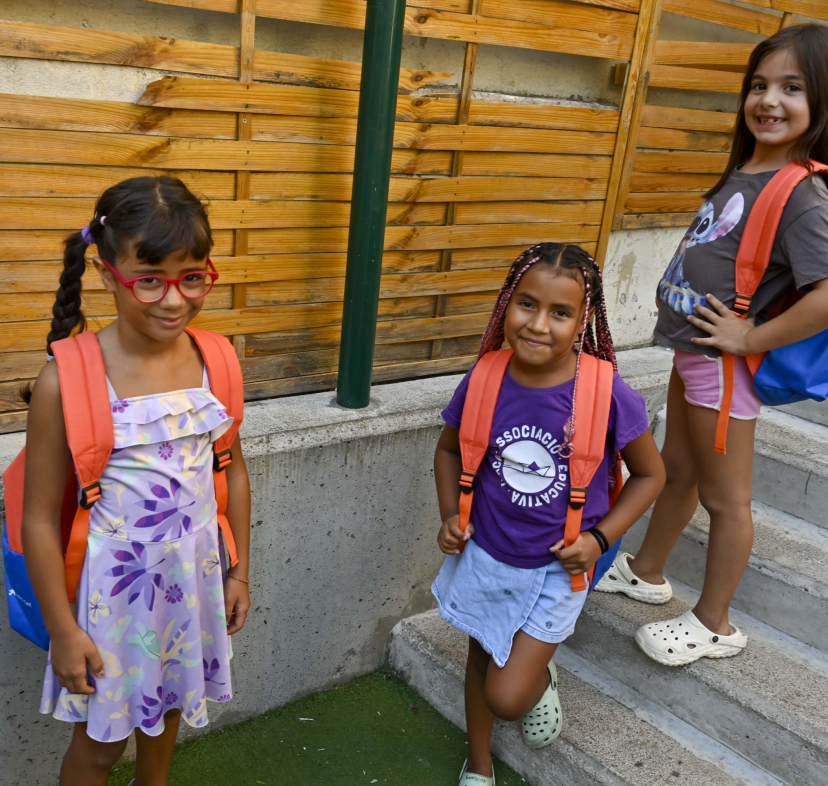 Tres nenes usuàries del programa CaixaProinfància amb les motxilles noves per afrontar el nou curs.
