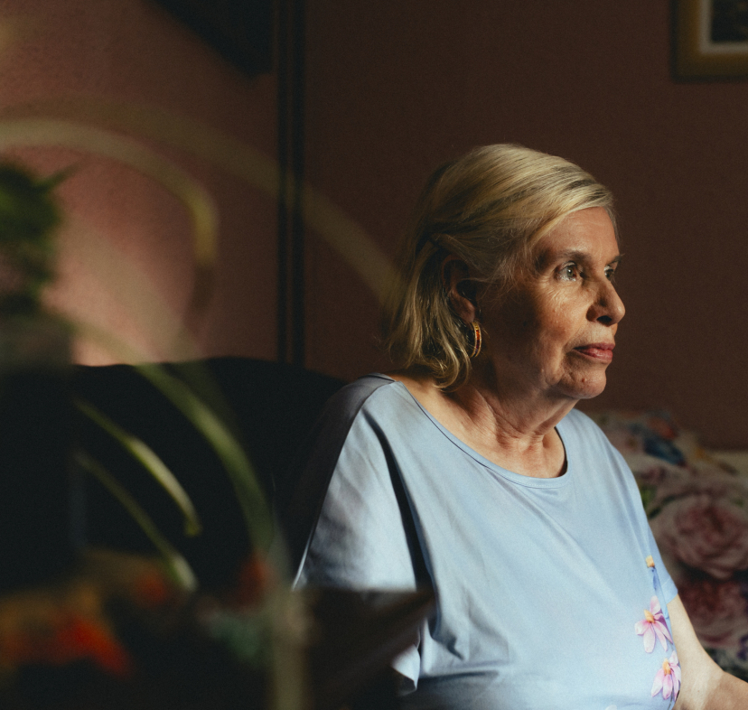 Una dona gran asseguda sola a casa seva.